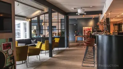 a living room with yellow chairs and a bar at Fosen Fjord Hotel in Å i Åfjord