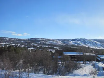 a building in the snow with mountains in the background at Fjelltun Fritidsleiligheter, leilighet 407 in Geilo