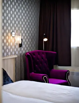 a bedroom with a purple chair next to a bed at Havila Hotel Raftevold in Hornindal