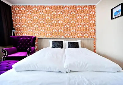 a bedroom with a white bed and a purple chair at Havila Hotel Raftevold in Hornindal