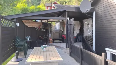 a patio with a wooden table and a black shed at Ålfotevegen 5 in Ålfoten