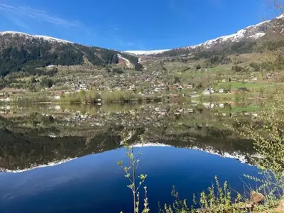 a reflection of a town in a lake with mountains at Voss Interlake in Skulestadmo
