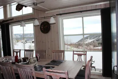 a dining room with a table and some windows at Luxury Mountain Villa in Strandlykkja