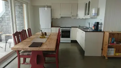 a kitchen with a wooden table with red chairs at Hjellup Fjordbo in Leksvik