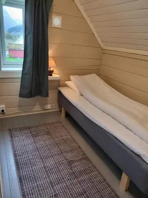 a small bedroom with a bed and a window at Solheim Gard in Stryn
