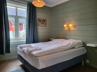 a bed in a room with green walls and a window at Solheim Gard in Stryn