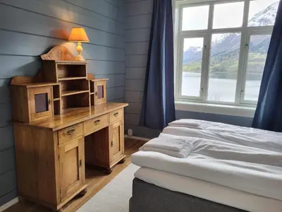 a bedroom with two beds and a desk and a window at Solheim Gard in Stryn