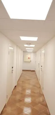 a hallway in an office building with white walls and a ceiling at Systra Hotel Søvik in Syvik