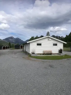 a white building with a bench in a parking lot at Fjellstova Ørskogfjellet Cottages in Sjøholt