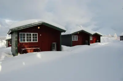 a couple of red buildings with snow on them at Fjellstova Ørskogfjellet Cottages in Sjøholt
