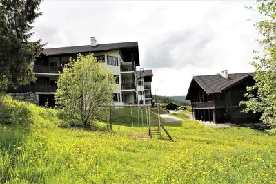 a building on a hill next to a field of grass at Alpin Apartments Sørlia in Hafjell