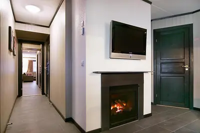 a living room with a fireplace and a tv on a wall at Alpin Apartments Sørlia in Hafjell
