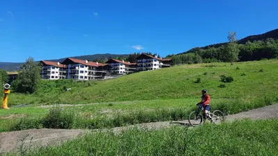 a person riding a bike on a hill with houses at Alpin Apartments Solsiden in Hafjell