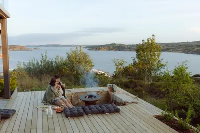 a woman sitting on a deck next to a fire pit at Panorama Hotell & Resort in Steinsland