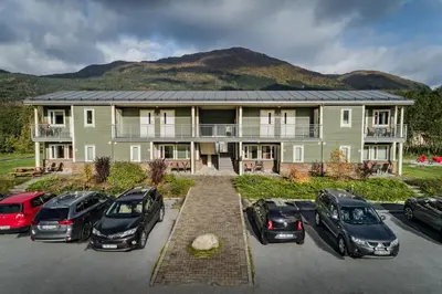 a large house with cars parked in a parking lot at Førde Gjestehus og Camping in Førde
