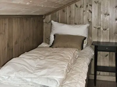 a bed in a room with a wooden wall at 5 person holiday home in Fåvang-By Traum in Favang