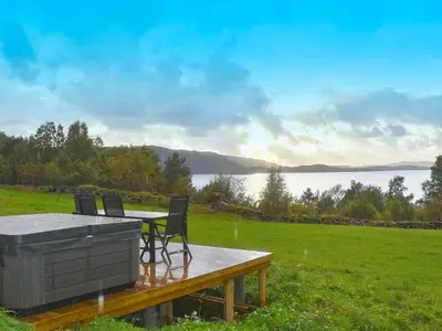 a table and chairs on a deck with a view of a lake at 8 person holiday home in Masfjordnes-By Traum in Masfjorden