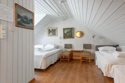 a attic bedroom with two beds and a table and chairs at Jaunsen Gjestgjevarstad in Granvin