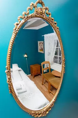 a mirror in a room with a bed and a chair at Jaunsen Gjestgjevarstad in Granvin