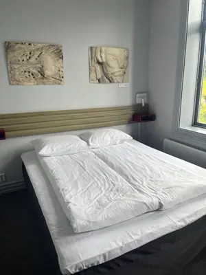 a bed with white sheets in a bedroom at Klosterhagen Hotel in Bergen