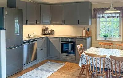 a kitchen with stainless steel appliances and a table with chairs at 3 Bedroom Cozy Home In Lavik in Lavik