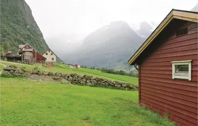 a red house in a field with mountains in the background at Stunning Home In Olden With Kitchen in Olden