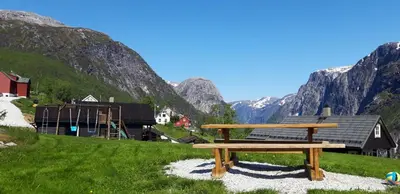 a wooden bench sitting in a field with mountains at Stalheim Fjord og Fjellhytter in Stalheim