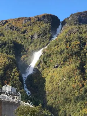 a waterfall in a mountain with a bridge at Øren Hotel in Høyanger