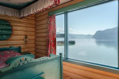 a bedroom with a view of the water and a window at Leikanger Fjordhotel - Unike Hoteller in Leikanger
