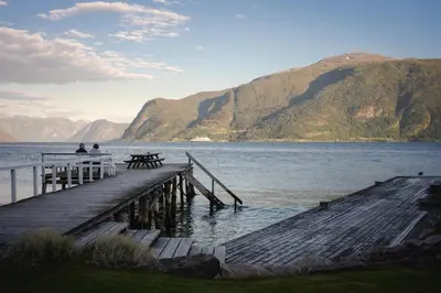 two people sitting on a dock over a body of water at Leikanger Fjordhotel - Unike Hoteller in Leikanger