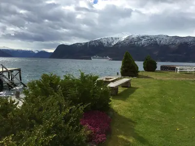 a bench sitting on the grass near a body of water at Leikanger Fjordhotel - Unike Hoteller in Leikanger