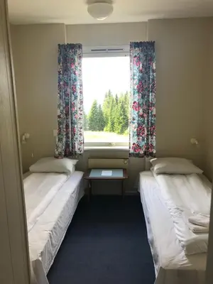 two beds in a small room with a window at Tronsvangen Seter in Alvdal