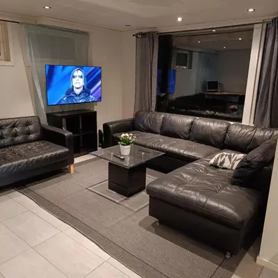 a living room with a leather couch and a flat screen tv at Malvik, Hundhamaren, Trondheim in Malvik