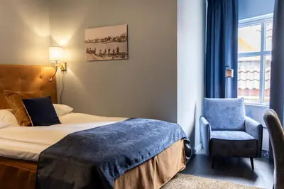 a bedroom with a bed and a chair and a window at Quality Hotel Florø in Florø