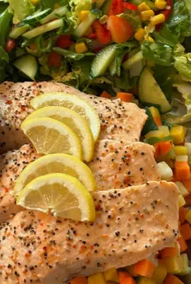 a plate of food with fish and vegetables with lemon slices at Eikum Hotel in Hafslo