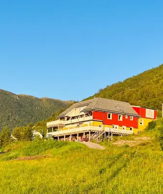 a large building on a hill in a field at Awesome Fishing, Boating and Nature Experience at Fiskesenter Birkeland in Rekdal