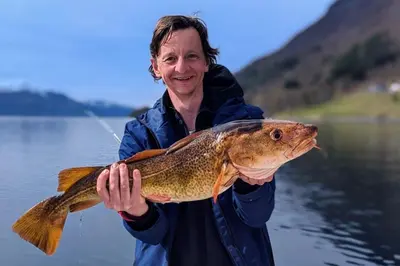 a man holding a large fish on a lake at Awesome Fishing, Boating and Nature Experience at Fiskesenter Birkeland in Rekdal