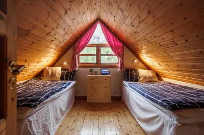 two beds in a wooden room with a window at Eastside Cottages in Bømlo
