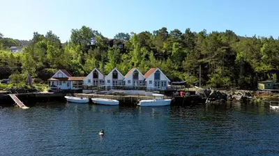 a house on a dock with boats in the water at Eastside Cottages in Bømlo