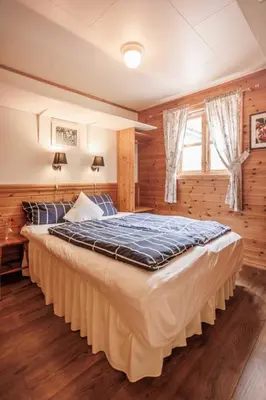 a large bed in a bedroom with wooden walls at Eastside Cottages in Bømlo