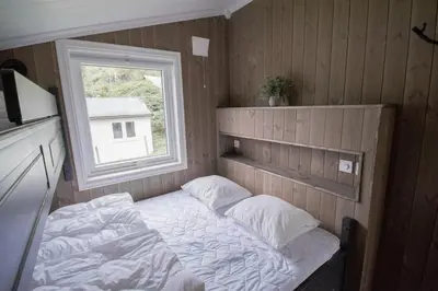 a small bed in a room with a window at Grande Hytteutleige og Camping in Geiranger