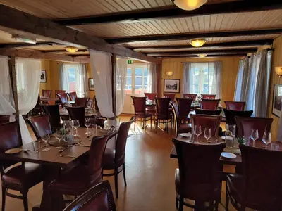 a restaurant with wooden tables and chairs and windows at Ona Havstuer - by Classic Norway Hotels in Ona