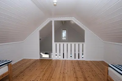 an attic room with white walls and wooden floors at Grandane Feriehus in Stongfjorden