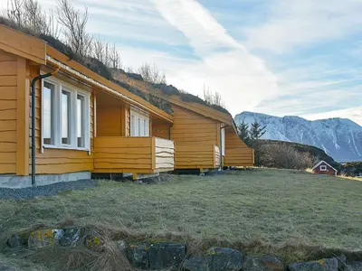 a wooden house with mountains in the background at 6 person holiday home in Aukra in Aukra