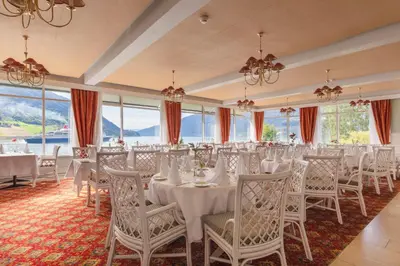 a banquet hall with white tables and chairs and windows at Olden Fjordhotel in Olden