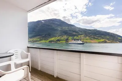 a balcony with a view of a boat on the water at Olden Fjordhotel in Olden