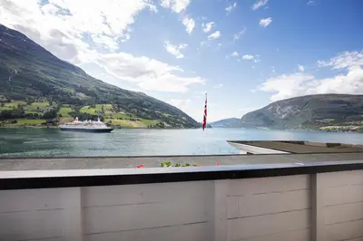 a boat on the water with a boat in the distance at Olden Fjordhotel in Olden