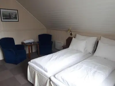 a bedroom with a bed and two blue chairs at Lunde Turiststasjon in Skei