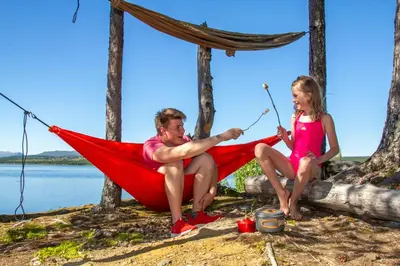 a man and a girl sitting in a hammock at Oset Fjellhotell in Gol