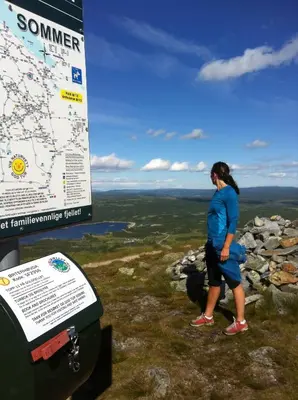 a woman standing on top of a mountain with a map at Oset Fjellhotell in Gol